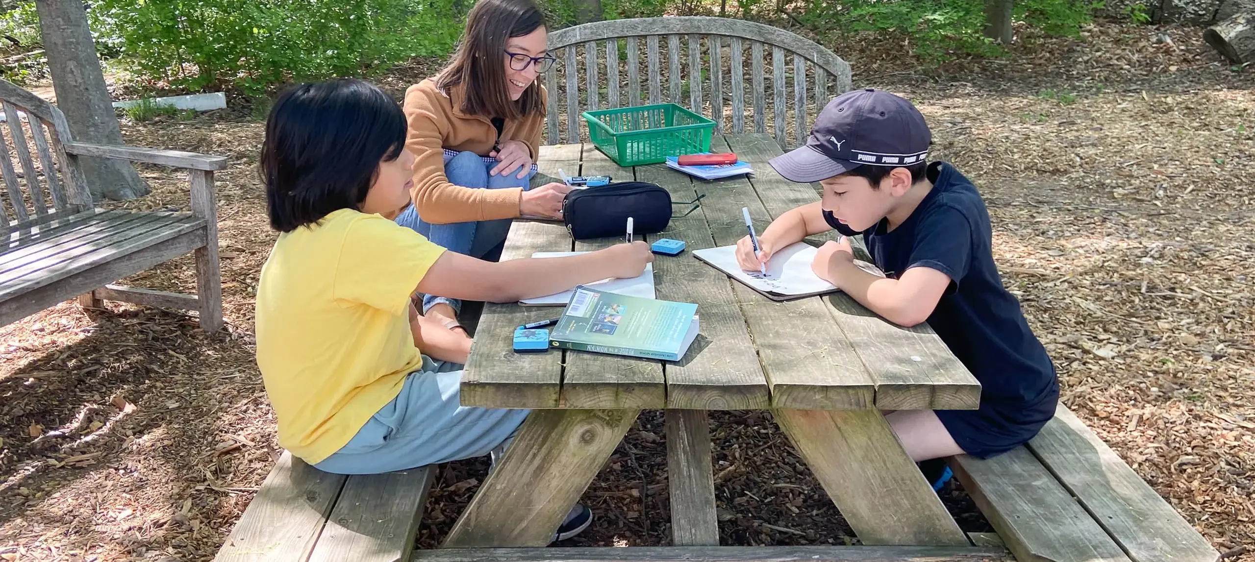 Students writing at picnic table