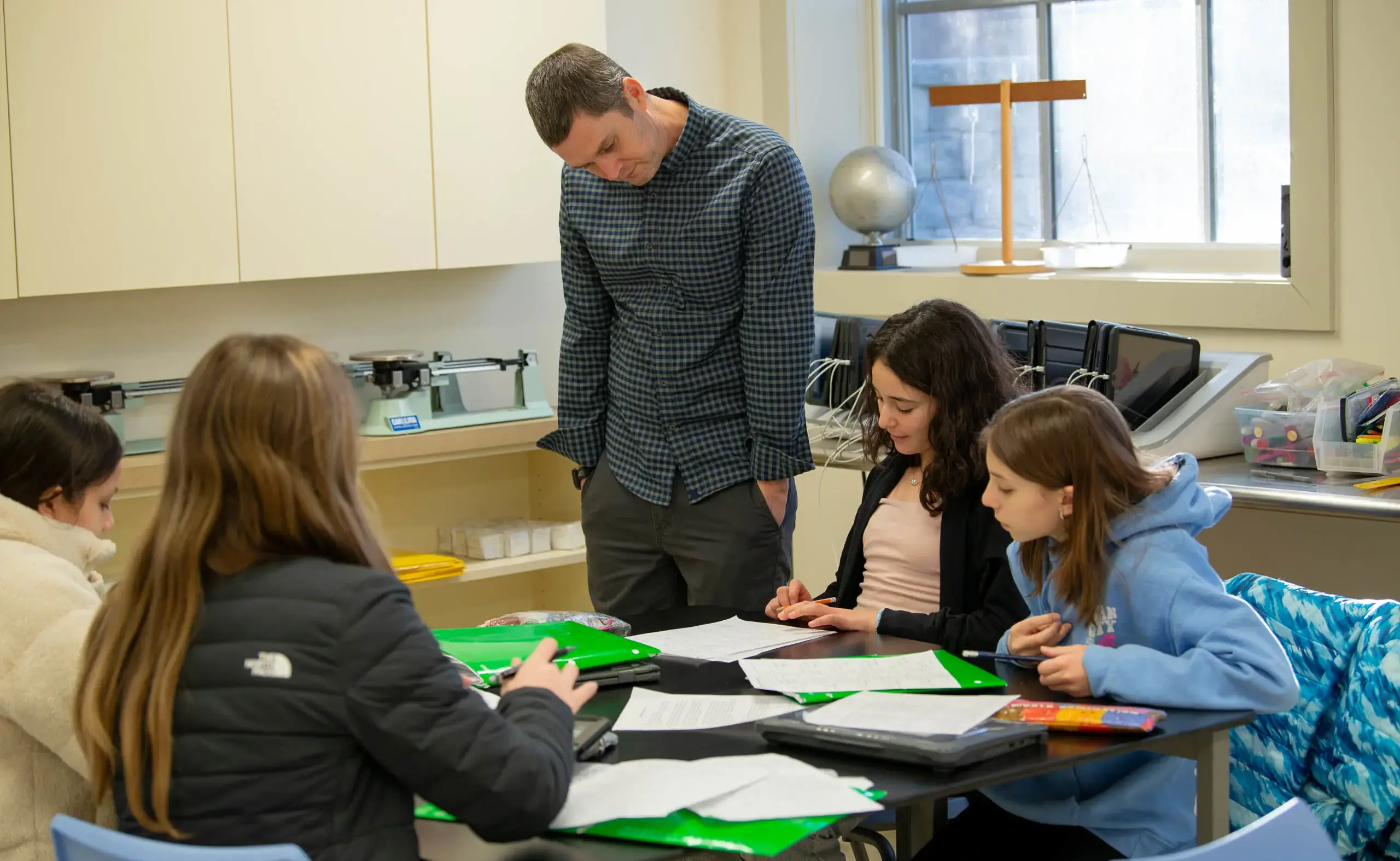 Teacher looking down at students as they work