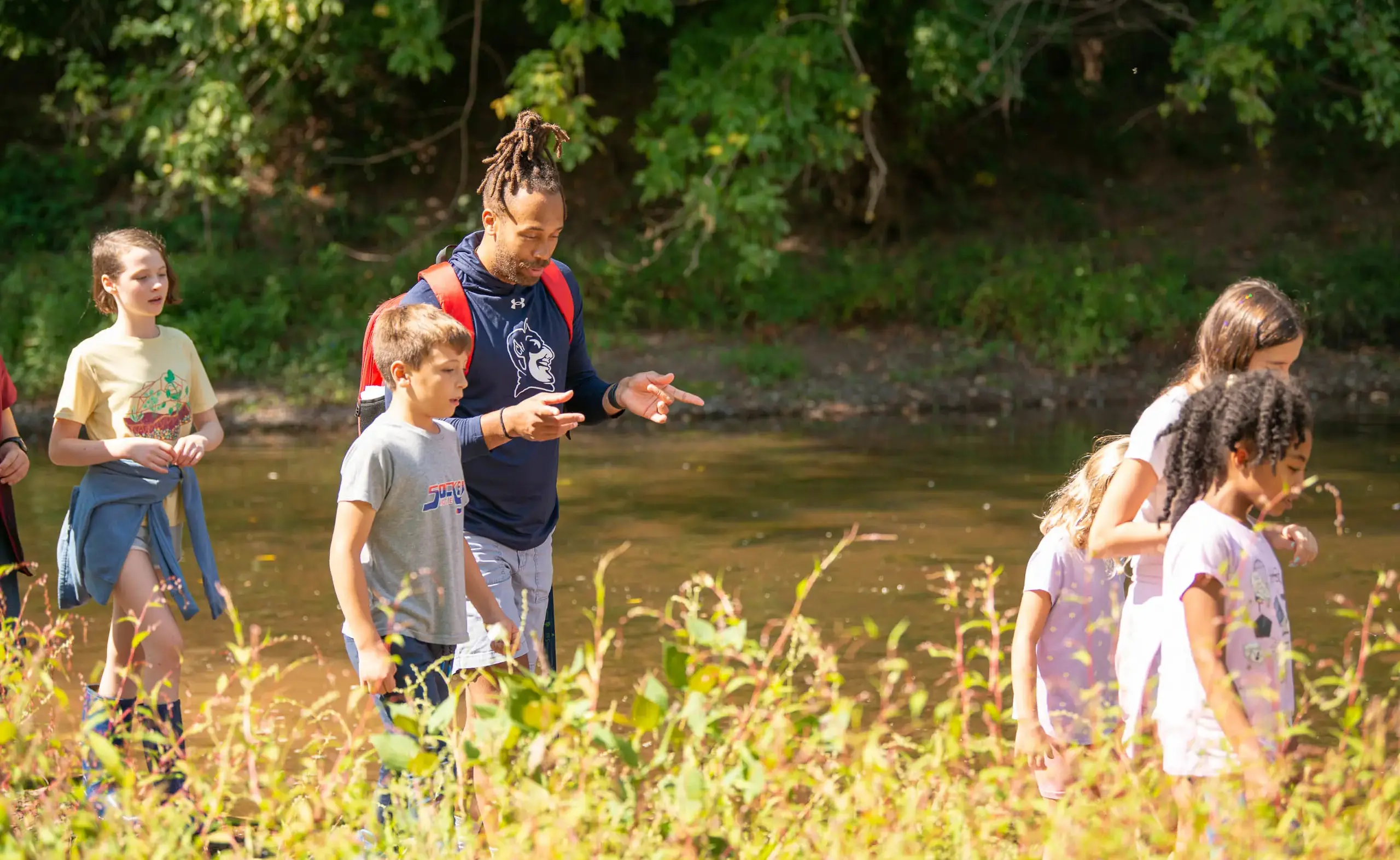 Teacher guiding students along a stream