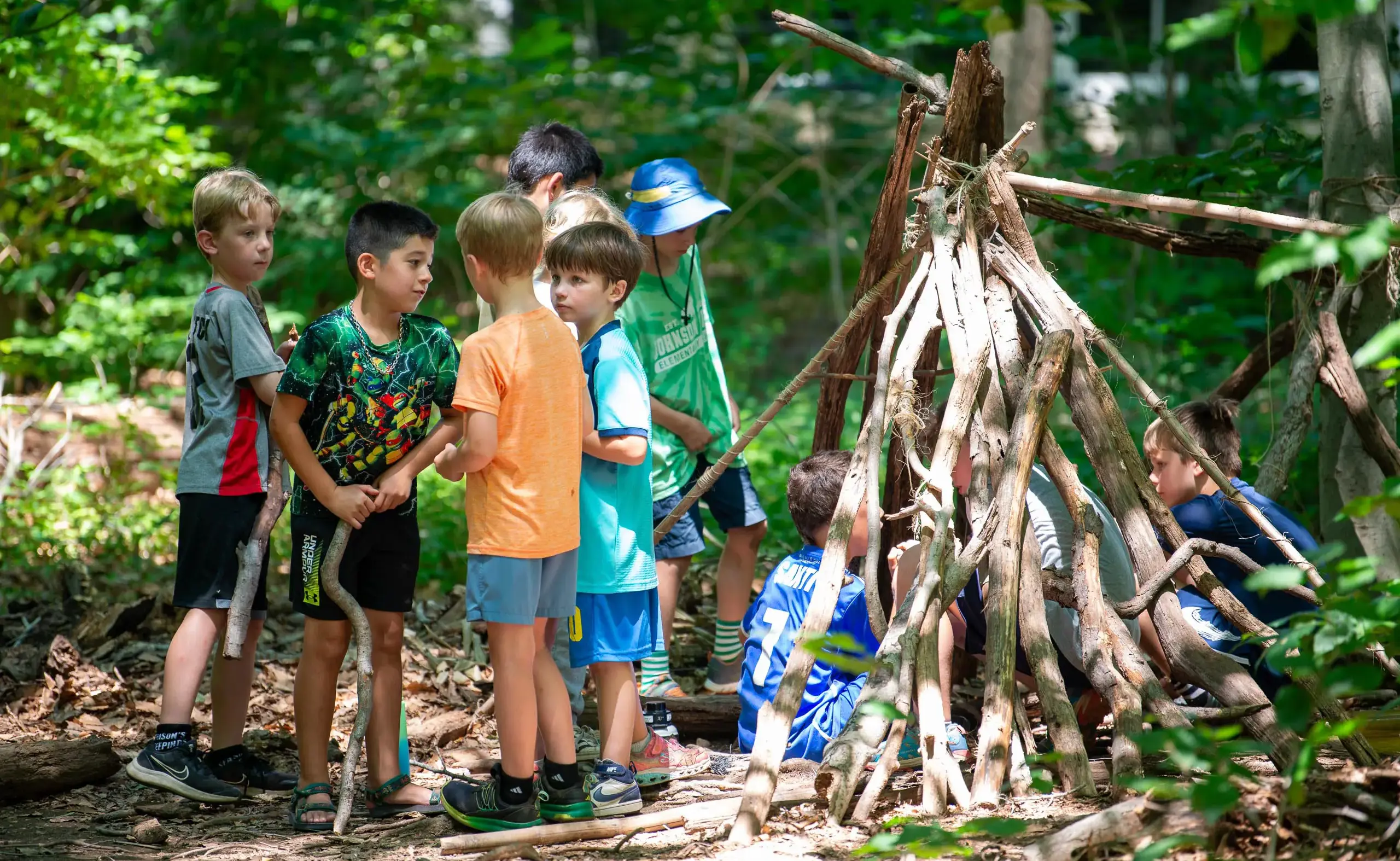 Students standing next to wood teepee