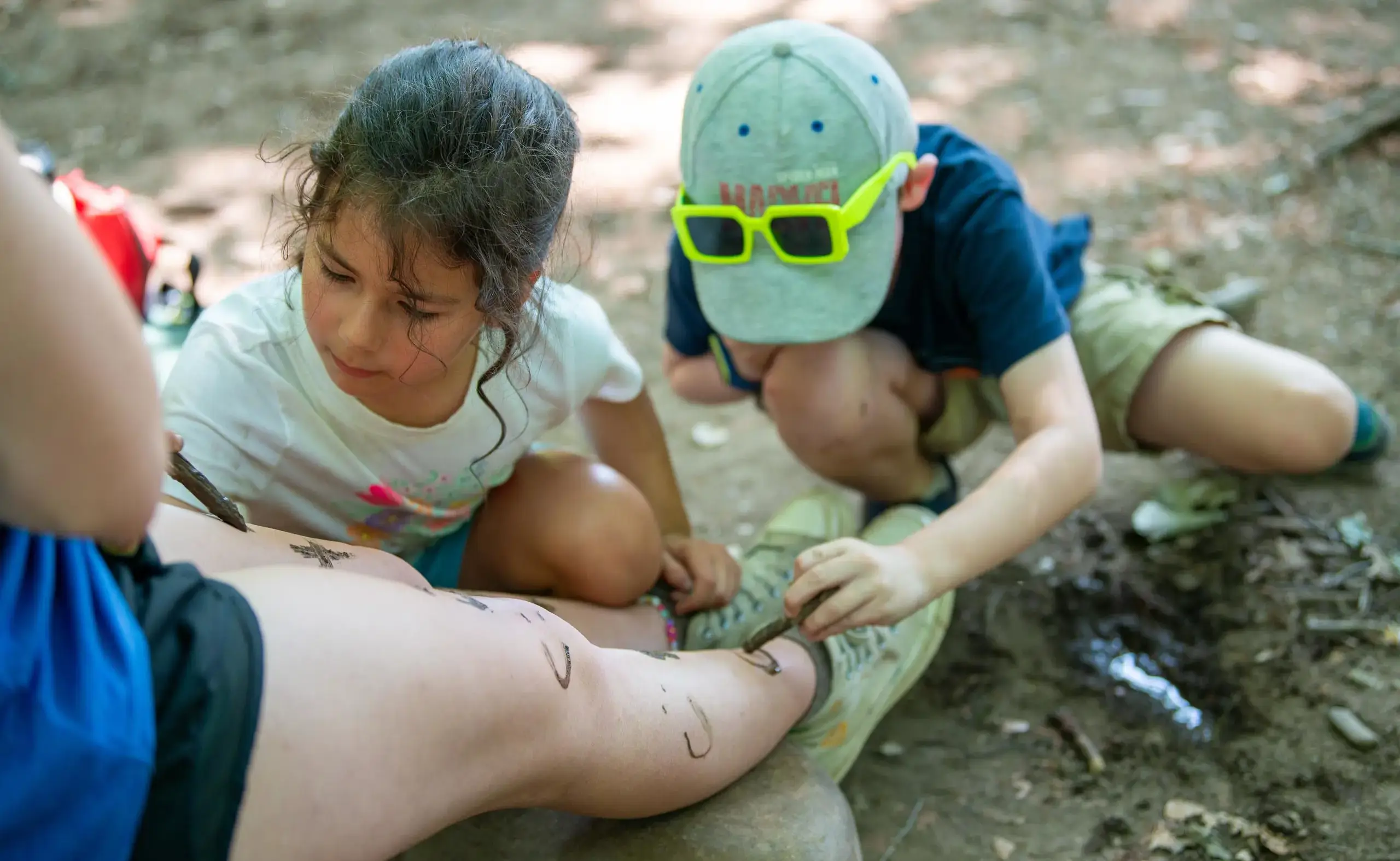 Children drawing faces on a leg